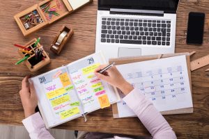 Tag planen mit Laptop, Kalender und Notizbuch